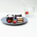 Traditional Australian lamington cakes with strawberry jam, chocolate and coconut. Against of a glass of water, a splash Royalty Free Stock Photo