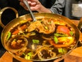 Traditional authentic Thai herbal soup food in brass hot pot: Hot and Sour Pork Soup in hot pot, Tom Yum Pork Soup, Tomyam Moo Too