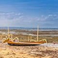 Traditional Balinese fishing boat stands on the ocean coast at low tide Royalty Free Stock Photo