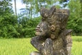 Traditional Balinese stone statuette of deity in the street near green rice terraces. Island Bali, Indonesia . Close up