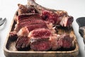 Traditional barbecue dry aged wagyu tomahawk steak sliced, on wooden serving board, on white stone background