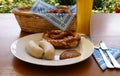 traditional Bavarian meal: white sausages, salty pretzels, sweet mustard, German beer, basket of prezels on Bavarian napk Royalty Free Stock Photo