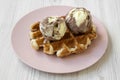 Traditional belgian waffle with icecream on pink plate over white wooden surface, side view. Close-up Royalty Free Stock Photo