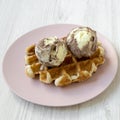 Traditional belgian waffle with icecream on pink plate on white wooden background, side view. Close-up Royalty Free Stock Photo