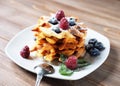 Traditional belgian waffles with fresh berrys and sugar powder on white plate, blue wooden background. Royalty Free Stock Photo