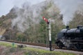 Black steam train on railway line track under hill near signal post