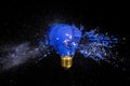 traditional blue bulb breaks and explodes on a black background