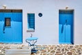 Traditional blue doors and windows and whitewashed walls of Greek houses. Midday summer sunshine, blue table