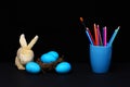 Traditional blue eggs in nest and mug with pencils and brush