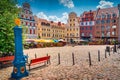 Traditional blue water pump with gryphon head crest from Szczecin city emblem and old town square in background