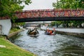 Traditional boat, Moliceiro, transporting tourists passing under bridge covered in confetti on canal at Aveiro, Portugal
