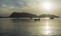 Traditional boats are laying on wave surface of the sea with a long big mountain, the sunrise in a morning, Thailand Royalty Free Stock Photo