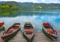 Traditional boats waiting for tourists on Lake Bled, with the lake island and charming little church in the background, famous Royalty Free Stock Photo