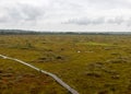 Traditional bog landscape with wet trees, grass and bog moss during rain, pedestrian wooden footbridge over the bog, foggy and Royalty Free Stock Photo