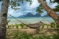 Traditional braided hammock in the shade with tropical island in the background