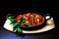 Traditional braised octopus, octopus with paprika in garlic tomato sauce and herbs in a cast iron pan