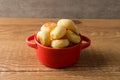 Traditional Brazilian Snack Cheese Bread in a rustic red cooking pot. On a wooden table background. with copy space