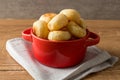 Traditional Brazilian Snack Cheese Bread in a rustic red cooking pot. On a wooden table background. with copy space