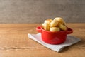 Traditional Brazilian Snack Cheese Bread in a rustic red cooking pot. On a wooden table background. with copy space