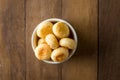 Traditional Brazilian Snack Cheese Bread in a white pot. On a wooden table background. copy space