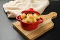 Traditional Brazilian Snack Cheese Breadin a rustic red cooking pot. on a black table background