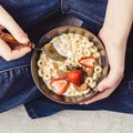 Traditional breakfast bowl. Cereal rings, strawberries and milk in bowl in teen hands Royalty Free Stock Photo