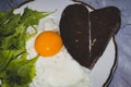 Traditional breakfast with fried egg protein and yolk, slices of heard-shaped bread and green spinach on white plate Royalty Free Stock Photo