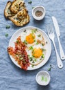 Traditional breakfast or snack - fried eggs, bacon, grilled bread on blue background, top view. Royalty Free Stock Photo