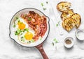 Traditional breakfast or snack - fried eggs, bacon, grilled bread on light background, top view.