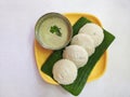 Idly and green chutney on a banana leaf