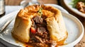 Traditional British dish steak and kidney pudding in suet pastry with gravy served on a plate. Delicious hearty comfort food Royalty Free Stock Photo