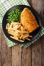 Traditional British food: Fish and chips with green peas close-up on a plate. Vertical top view Royalty Free Stock Photo