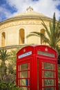 Mosta, Malta - Traditional British red telephone box with palm trees and the famous Mosta Dome at background