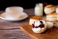 Traditional British Scones with Cream cheese, Cranberry jam and a cup of tea on wooden black background