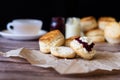 Traditional British Scones with Cream cheese, Cranberry jam and a cup of tea on wooden table