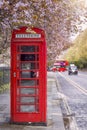 A traditional, british telephone booth under a tree in full spring blossom Royalty Free Stock Photo