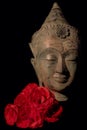 Traditional Buddha head statue with red roses. Buddhism and love