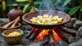Traditional campfire cooking of sliced plantains on woodfire with clay pot and baskets Royalty Free Stock Photo