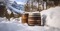 Traditional casks against a snowy mountain landscape in winter. Barrel cylindrical container made of brown wooden staves bound by