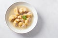 Traditional Catalan Christmas dish Escudella in white plate on table, stuffed pasta in meat broth, top view