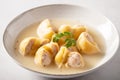 Traditional Catalan Christmas dish Escudella in white plate on table, stuffed pasta in meat broth, top view