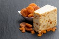 Traditional cheddar cheese with dry apricot on black stone background
