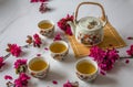 Traditional cherry blossom decorated Japanese tea set filled with green tea and fresh red cheery blossom