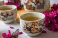 Traditional cherry blossom decorated Japanese tea set filled with green tea and fresh red cheery blossom