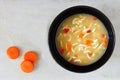 Traditional chicken noodle soup, overhead view on white marble