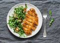 Traditional chicken schnitzel with arugula cherry tomatoes salad on grey background