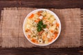 Traditional chicken soup with noodles, vegetables and parsley leaves on a textured burlap which is on rustic wooden background Royalty Free Stock Photo