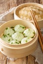 Traditional chinese baozi steam buns in a bamboo steamer basket close-up. Vertical