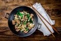 Traditional chinese mongolian beef stir fry in chinese cast iron wok with cooking chopsticks, wooden background. Top Royalty Free Stock Photo