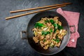 Traditional chinese mongolian beef stir fry in chinese cast iron wok with cooking chopsticks, stone slate background Royalty Free Stock Photo